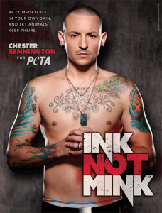 Tattooed man looks at camera, he is shirtless, hand in fist