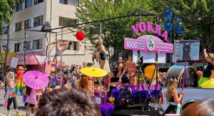 Parade float with many women in underwear and lingerie dancing on poles. A kitten adoption group.