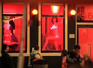 Men walking through red light district with women's bodies in the windows