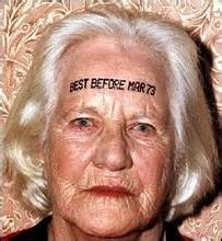 Closeup of an older woman's face. She has "BEST BEFORE MAR 73" printed across her forehead.