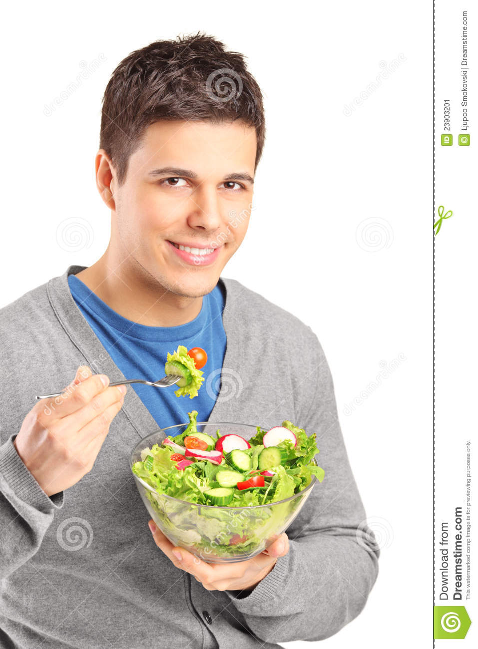 Man about to eat a forkfull of salad, smiles softly to camera